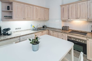 Eine Küche mit hellen Holzschränken, einer Granitarbeitsplatte, einem eingebauten Backofen und einem Spülbecken.