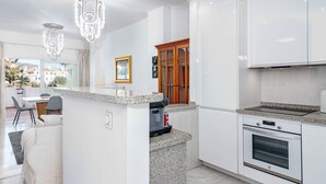 A modern kitchen with granite countertops, white cabinetry, a built-in oven, and a dining area with a table and chairs. - Rg325 - Great 2 Bed Apt, Close to Puerto Banus (Marbella)