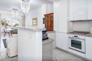 A modern kitchen with granite countertops, white cabinetry, a built-in oven, and a dining area with a table and chairs. - Rg325 - Great 2 Bed Apt, Close to Puerto Banus (Marbella)