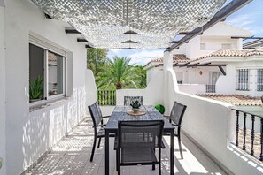 An outdoor patio with a table and chairs, a pergola overhead, and a view of a palm tree and buildings in the background. - Lnm5.30 - Great Location With Private Roof Terrace (Marbella)