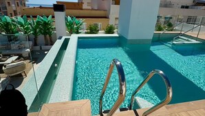 A rooftop pool with clear blue water, surrounded by lounge chairs and potted plants. - Le2c Luxury New Build Apartment Near the Beach (Estepona)