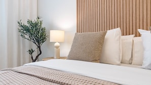 A neatly made bed with a patterned bedspread, a bedside lamp, and a small potted plant. - Le2c Luxury New Build Apartment Near the Beach (Estepona)