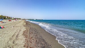A beach with people sunbathing, a clear sky, and a calm sea. - Le2c Luxury New Build Apartment Near the Beach (Estepona)