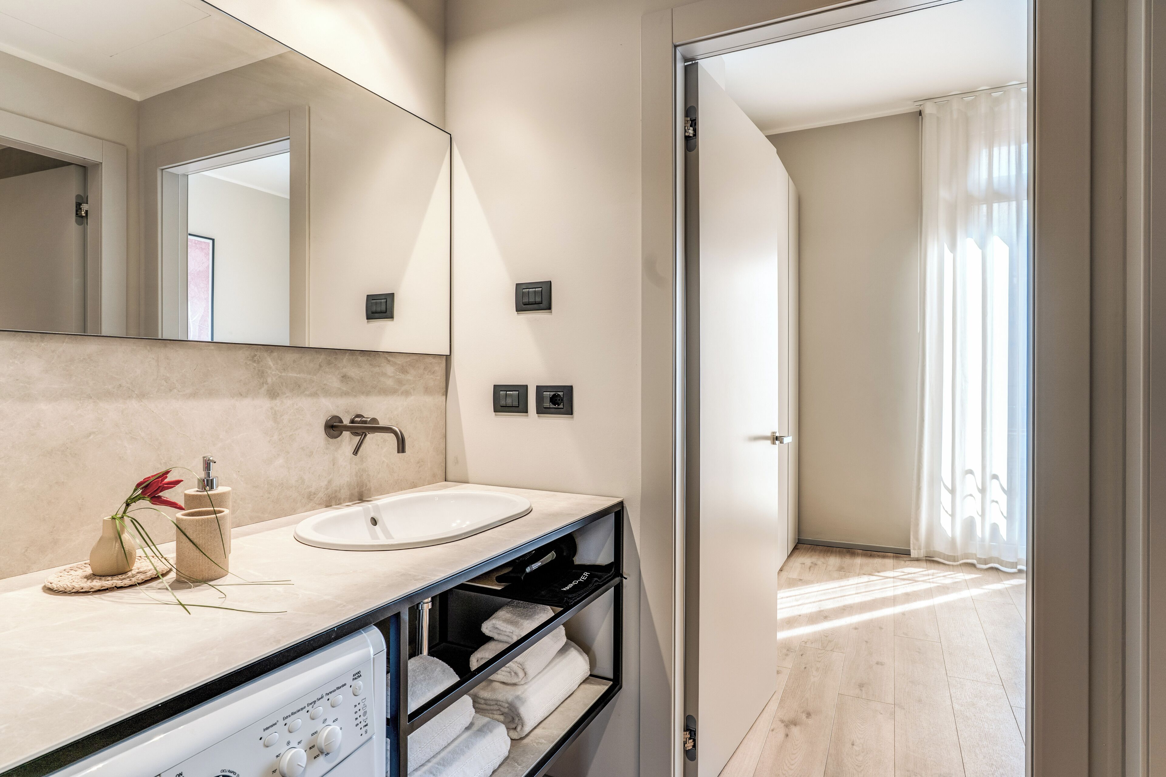 A modern bathroom with a large mirror, a sink, and a towel rack.
