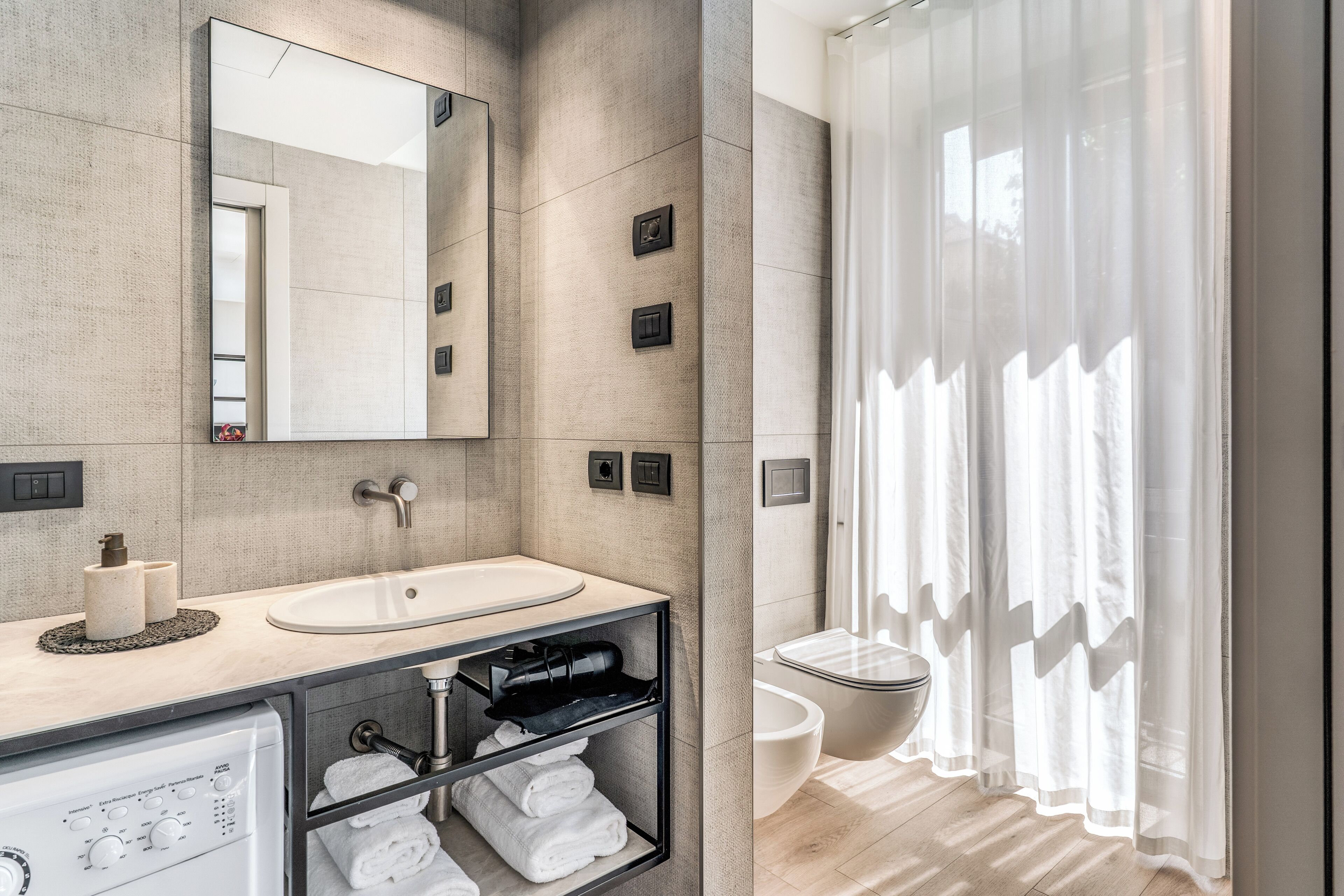 A modern bathroom with a large mirror, a sink, a toilet, and a shower curtain.
