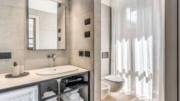 A modern bathroom with a large mirror, a sink, a toilet, and a shower curtain.