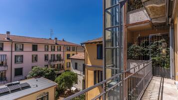 A multi-story residential building with balconies, a clear sky, and a courtyard with trees.