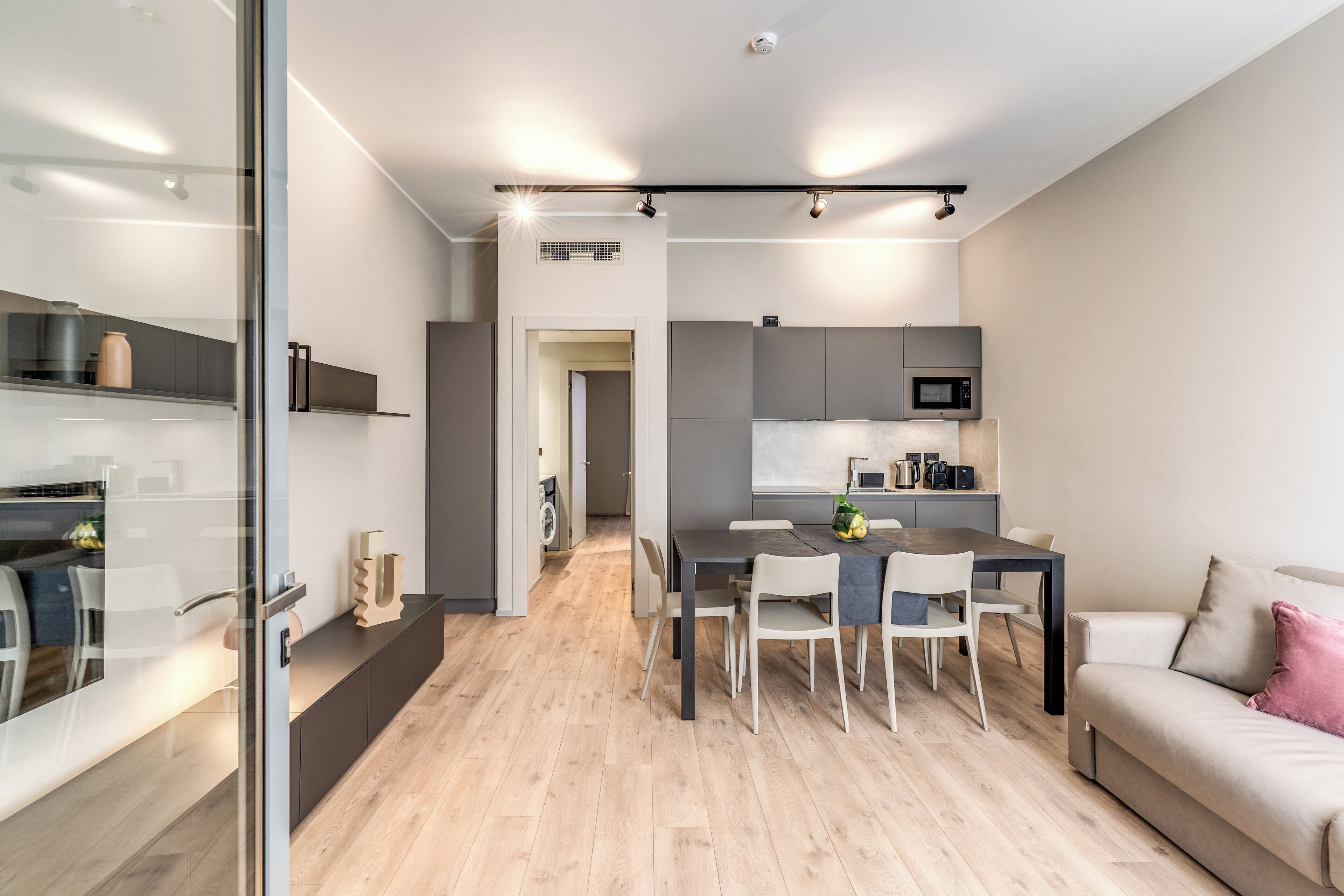 Una cocina moderna con microondas y armarios, un comedor con mesa y sillas, y un sofá en la sala de estar.