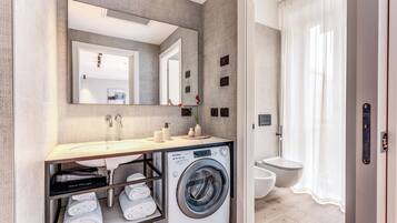 Un bagno moderno con lavatrice integrata, uno specchio grande e il water.