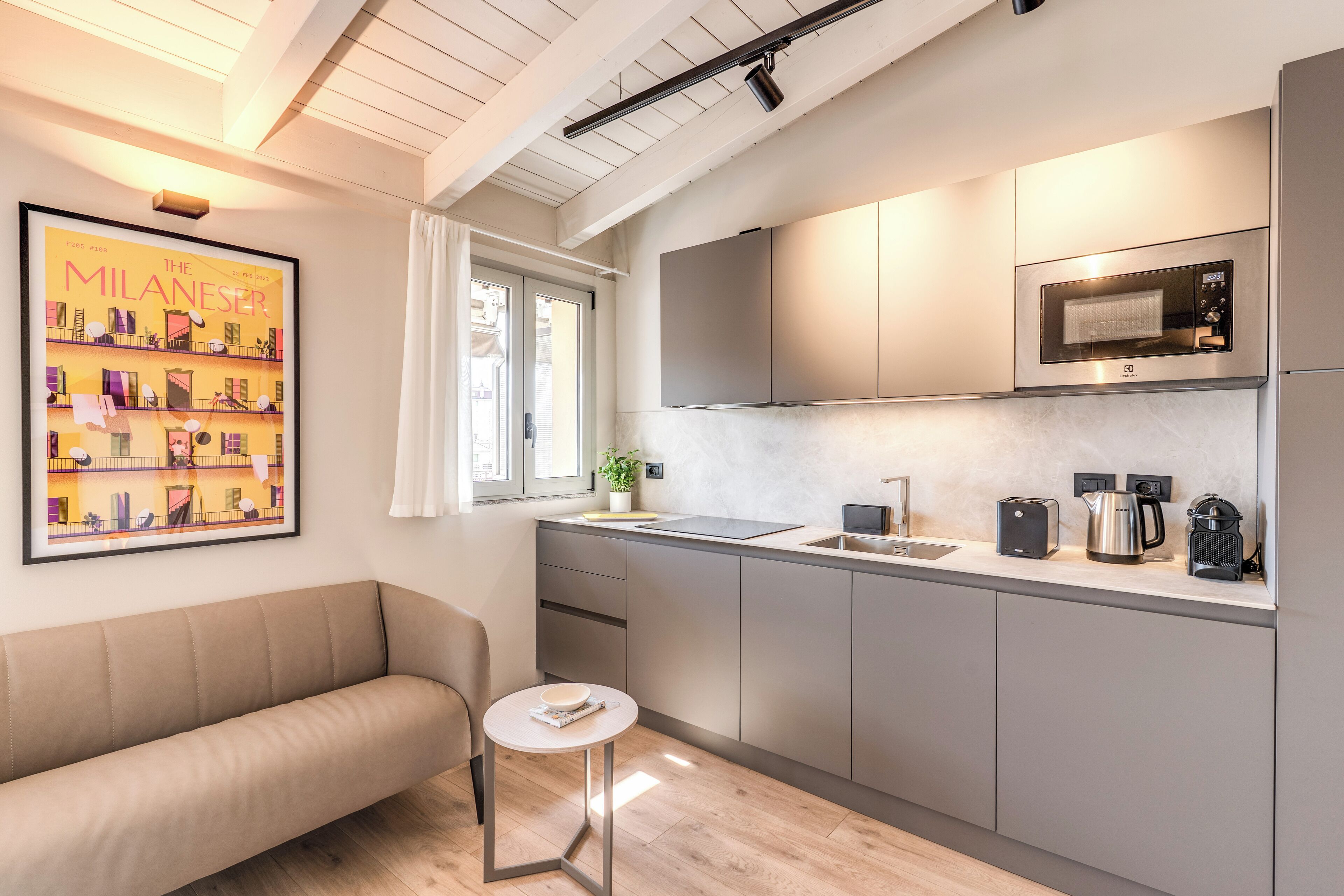 Una cucina moderna con forno a microonde, macchina del caffè e bollitore sul piano di lavoro.