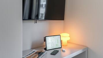 Uma mesa com um tablet mostrando um mapa, um smartphone, uma luminária e um jornal.