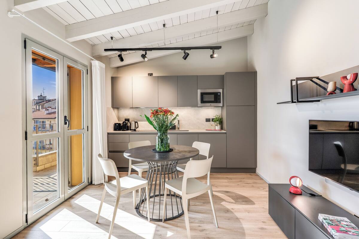 A modern kitchen with a dining area, large windows, and a view of the outside.