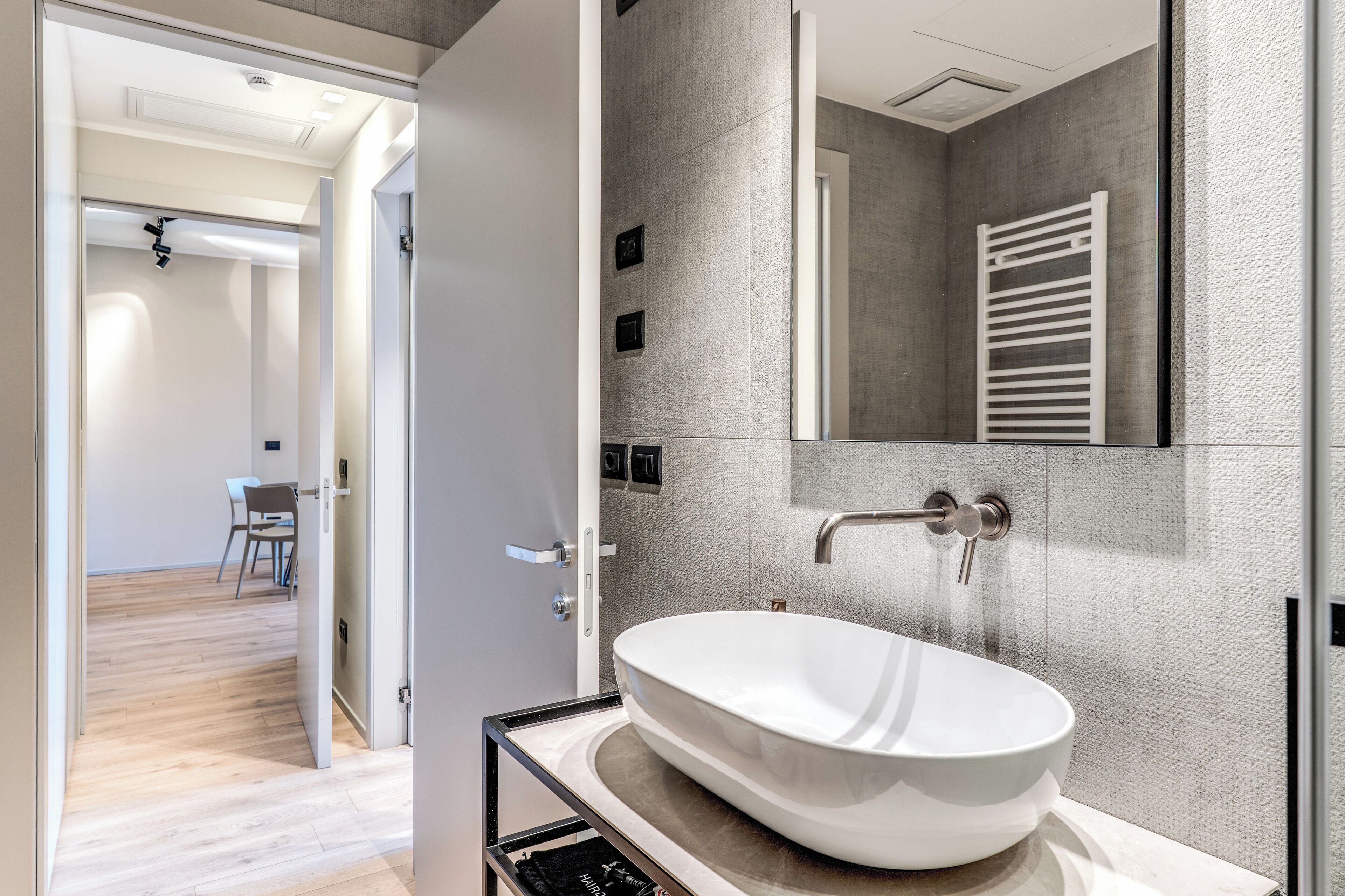A modern bathroom with a large oval sink, a mirror, and a towel rack.