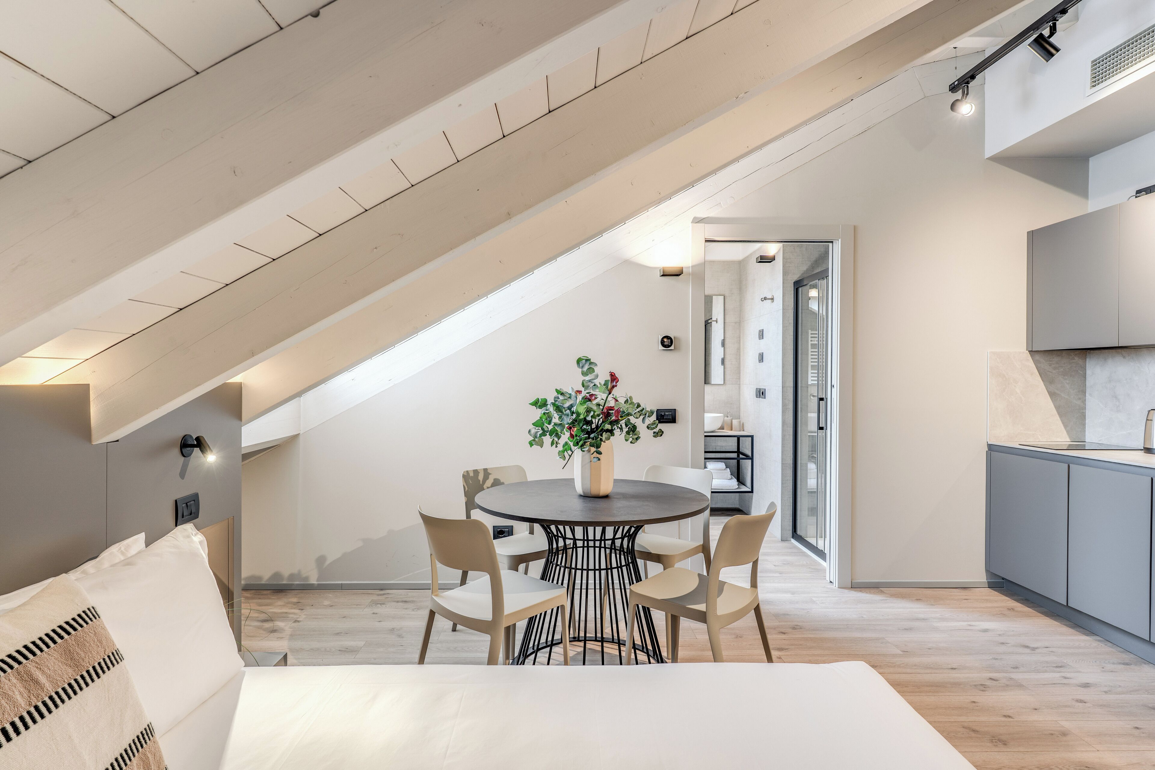 Un dormitorio estilo loft moderno con techo inclinado, una mesa redonda de comedor con sillas y una planta en maceta.