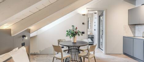 Un dormitorio estilo loft moderno con techo inclinado, una mesa redonda de comedor con sillas y una planta en maceta.