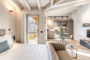 A modern hotel room with a large bed, a sofa, a small table, and a kitchenette in the background. - Seety Porta Romana Dimora (Milan)