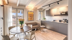 Un apartamento moderno con zona de comedor, sofá, cocina y grandes ventanales con vistas a la ciudad.