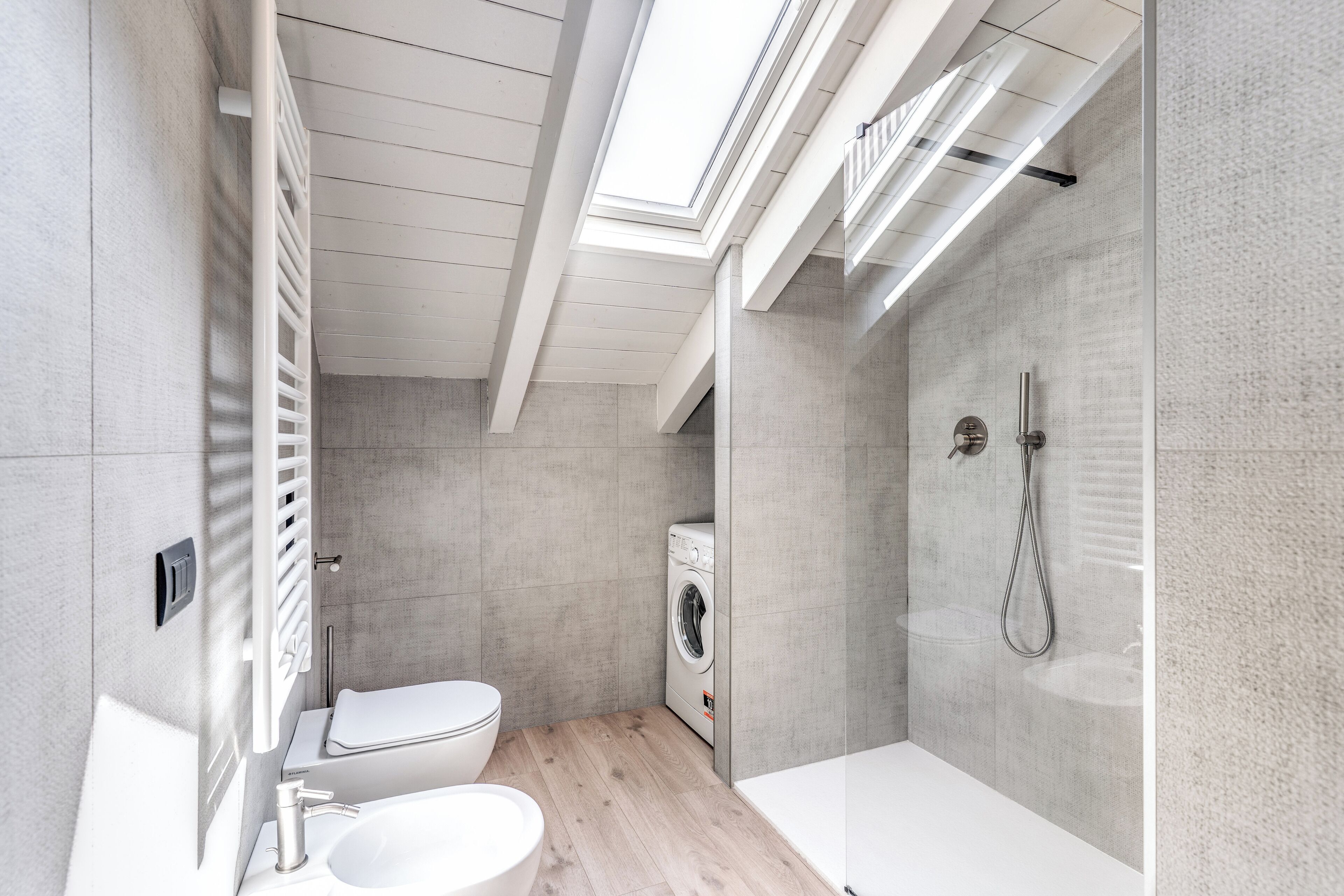 Une salle de bain moderne avec un puits de lumière, un lave-linge, des toilettes et une baignoire.