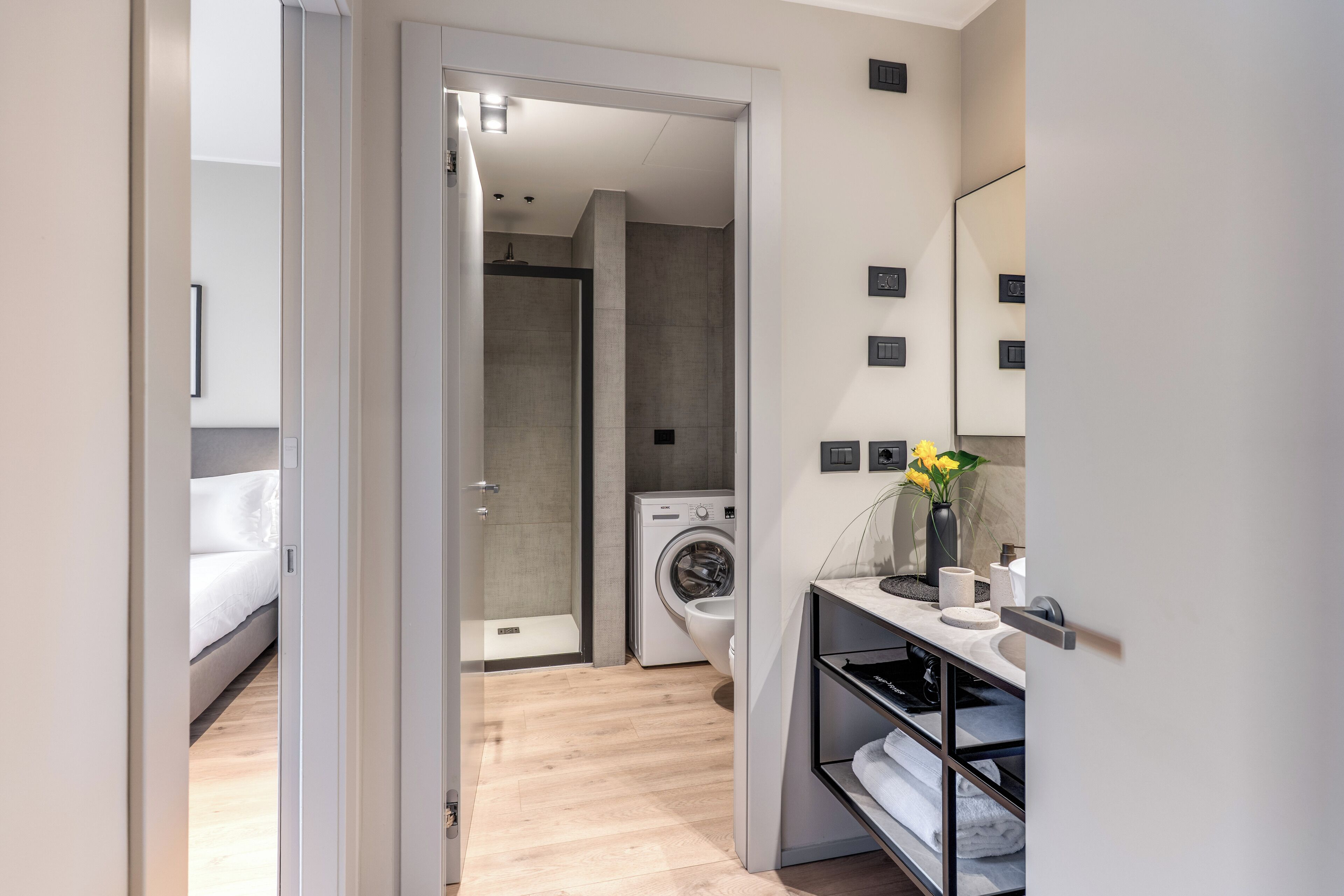 A modern bathroom with a shower, toilet, and washing machine.
