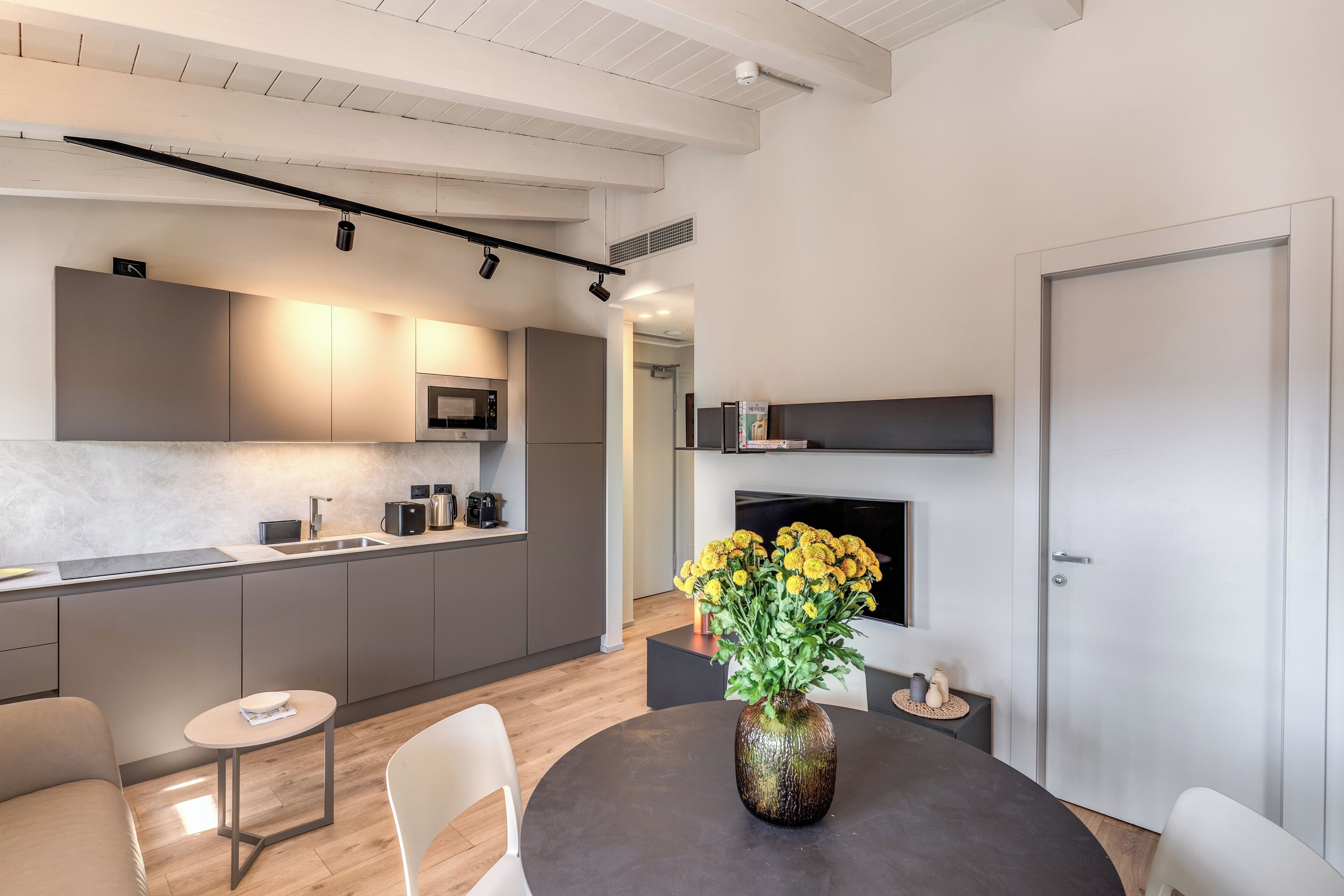 A modern kitchen with grey cabinets, a microwave, and a dining area with a round table and chairs.