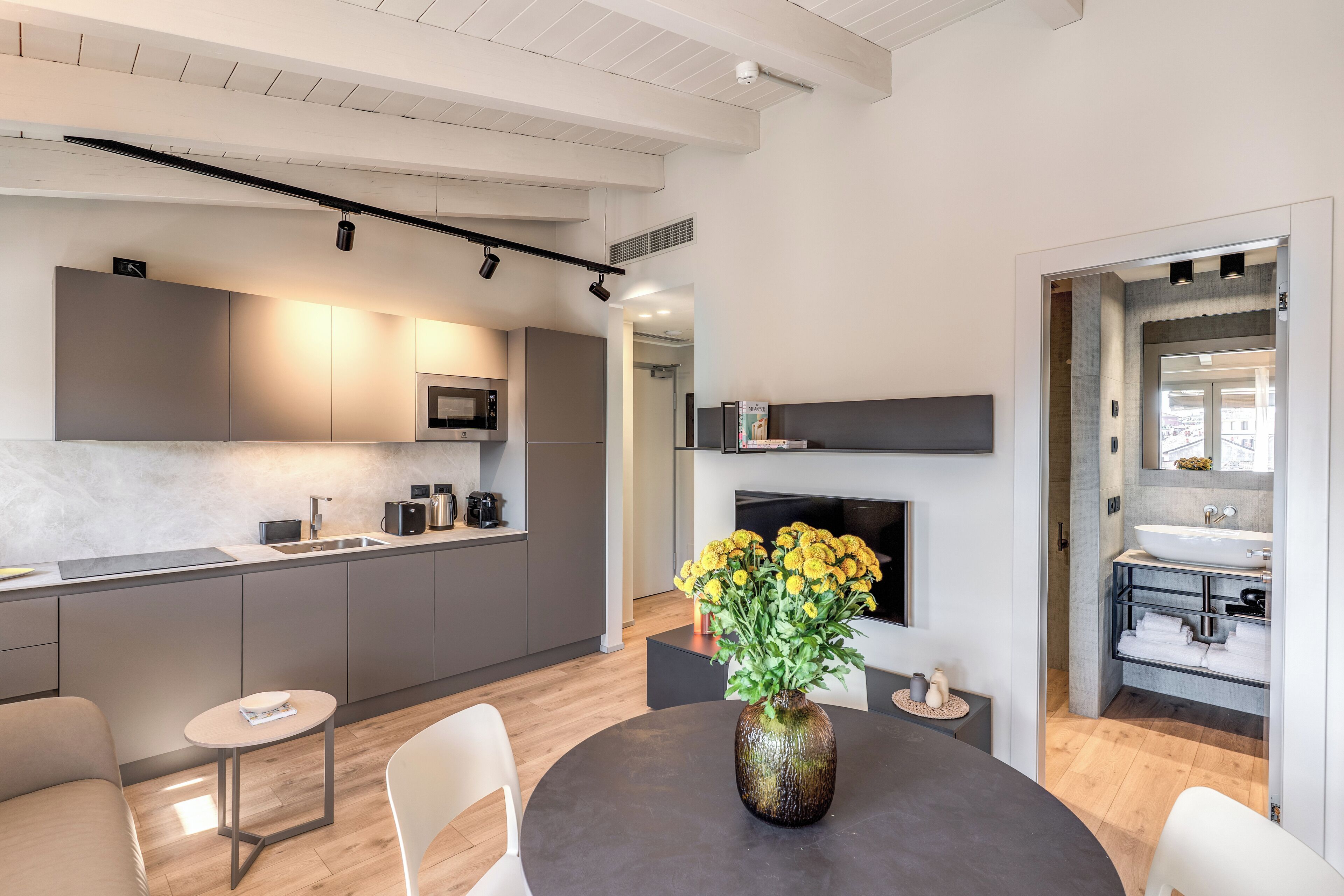 A modern kitchen with grey cabinets, a microwave, and a dining area with a round table and chairs.