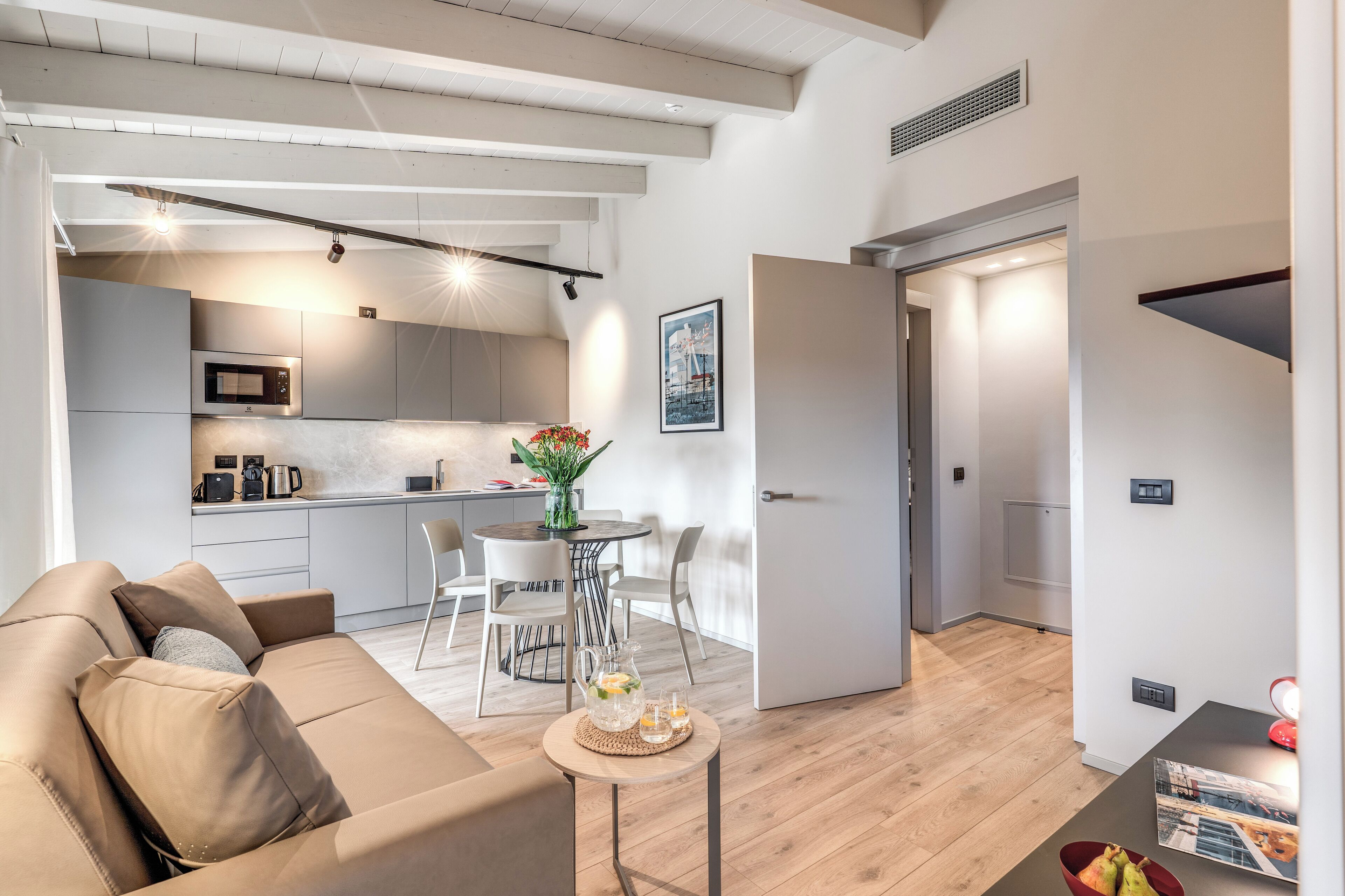 A modern apartment with a living area, kitchen, dining space, and a staircase.