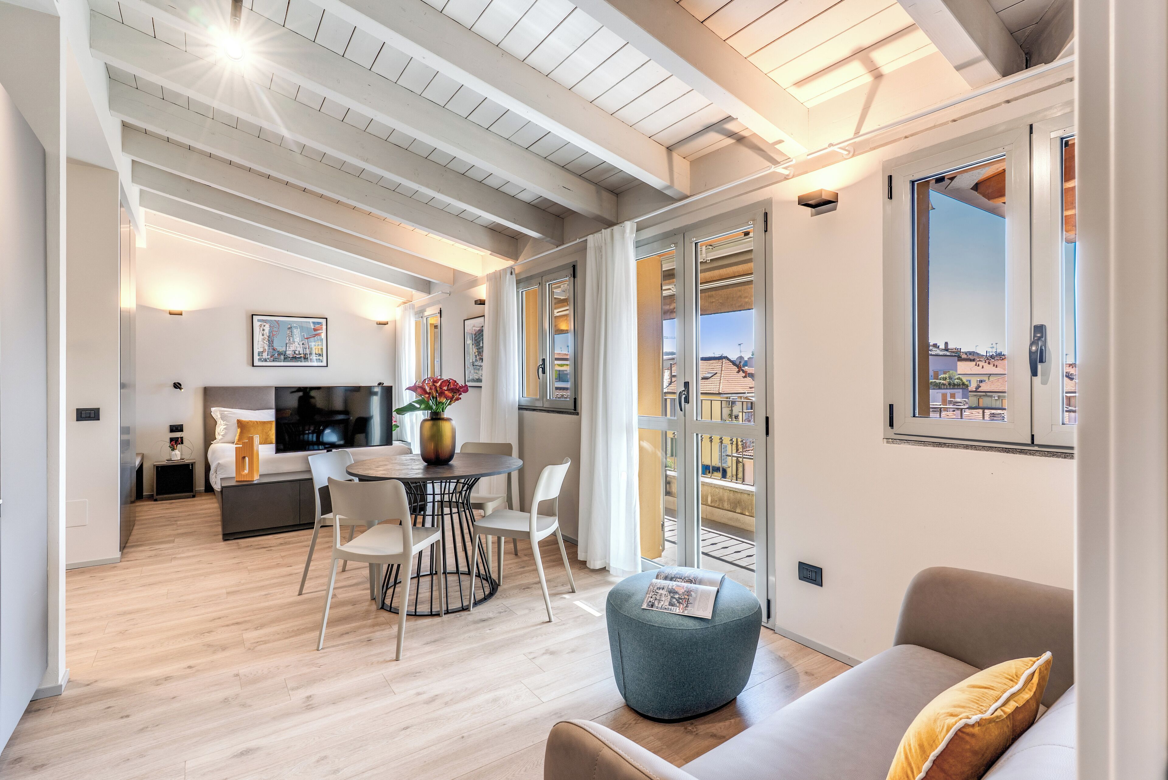 Un intérieur moderne comprenant un coin repas, un canapé et un balcon offrant une vue sur la ville.