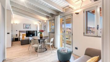 A modern interior with a dining area, a sofa, and a balcony with a city view.