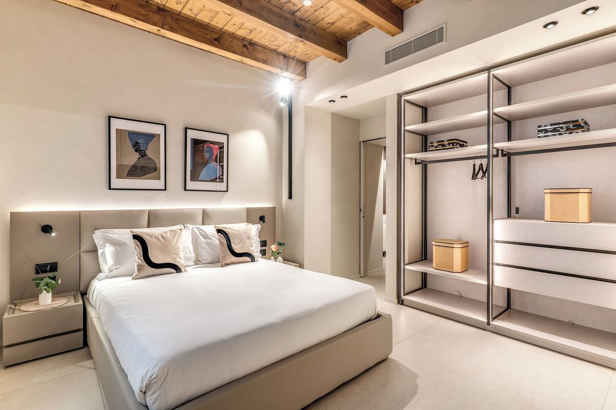 Un dormitorio moderno con una cama grande, un vestidor y obras de arte en la pared.