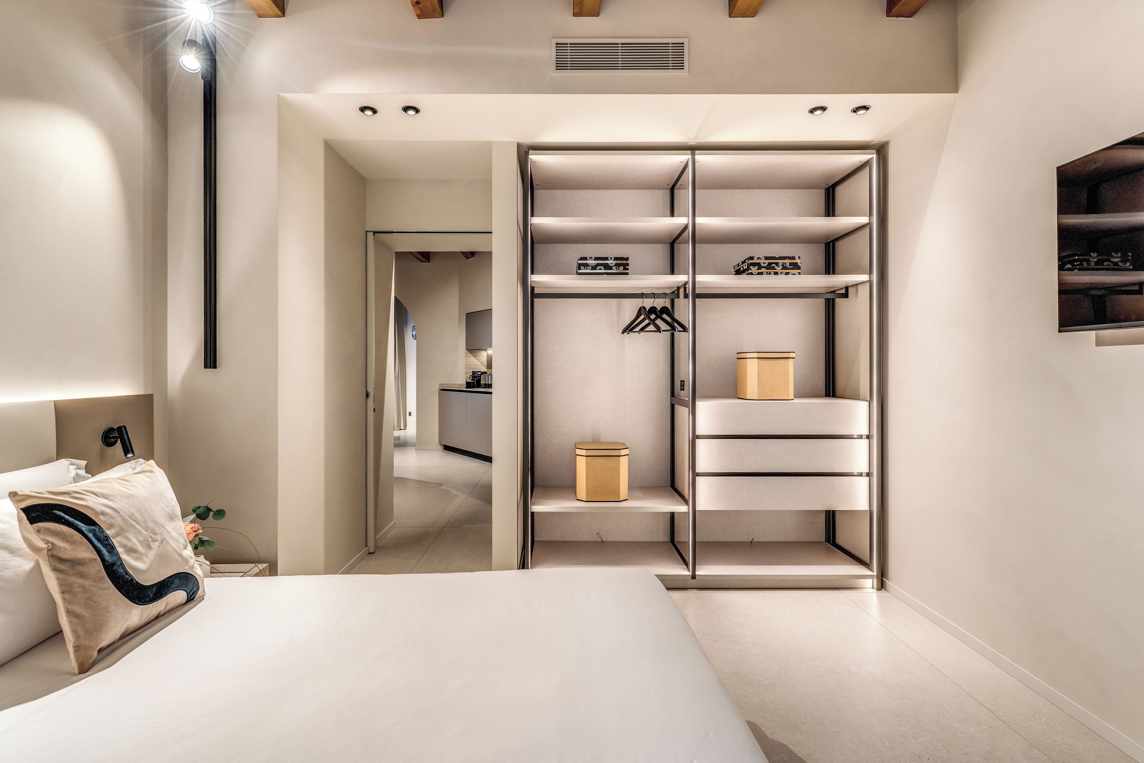 A modern bedroom with a large bed, a walk-in closet, and a minimalist design.