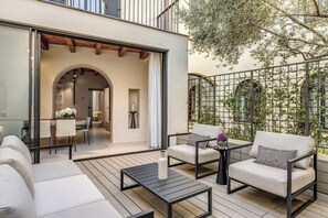 Une terrasse extérieure aménagée avec un canapé, deux fauteuils, une table basse et un coin repas.