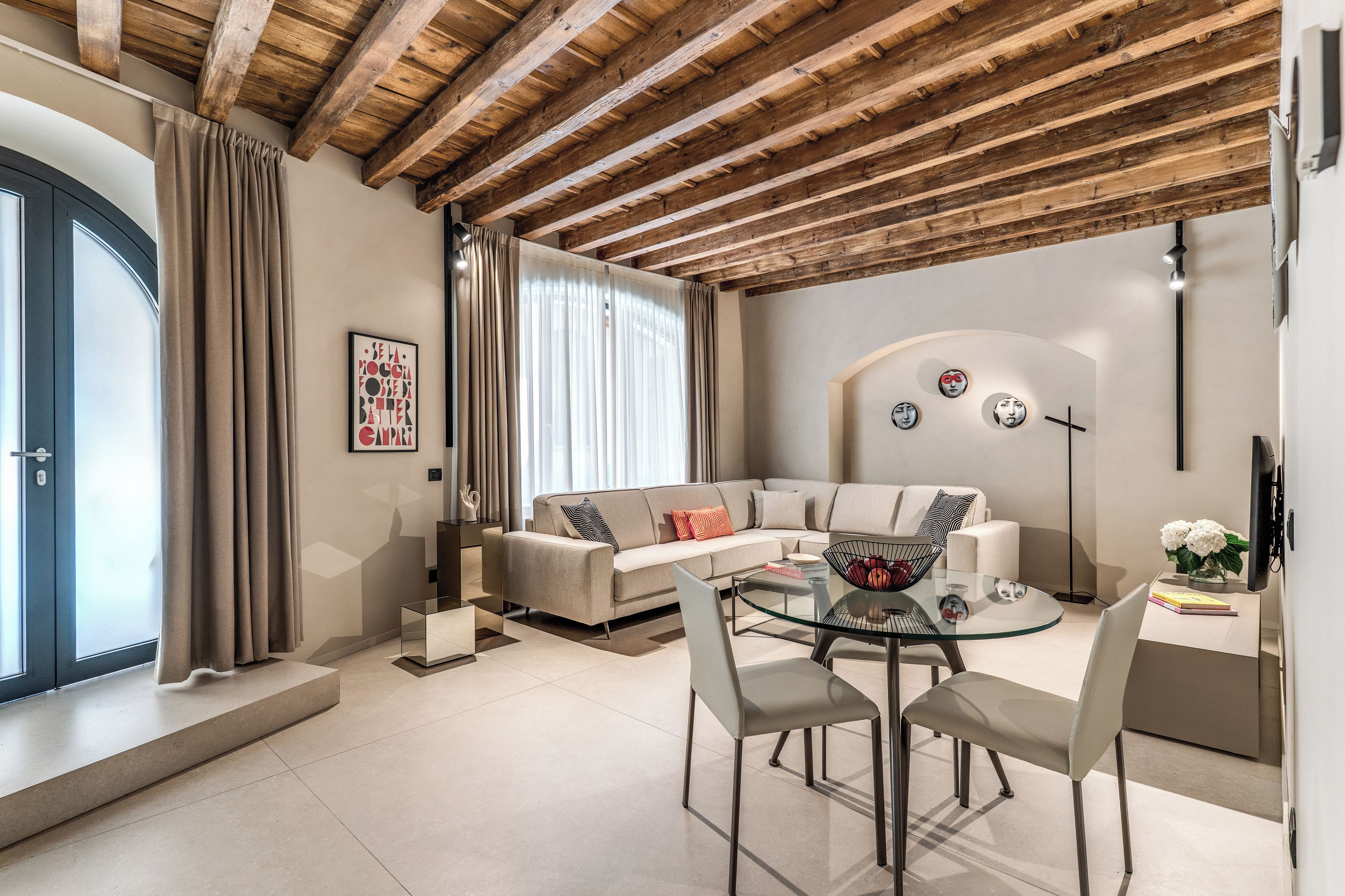 A modern living room with a sofa, glass coffee table, and chairs.