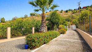 A pathway lined with a palm tree, red flowers, and a stone wall. - Holiday villa with pool & fantastic views, Coin (Coín)