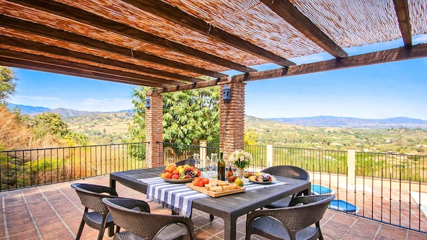An outdoor patio with a table set for a meal, surrounded by wicker chairs, and overlooking a scenic landscape. - Holiday villa with pool & fantastic views, Coin (Coín)