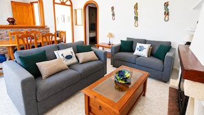 Ein Wohnzimmer mit zwei grauen Sofas, einem Holztisch und einem Essbereich mit einem Holztisch und Stühlen.
