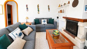 A living room with two grey sofas, a wooden coffee table, a fireplace, and decorative wall hangings. - Holiday villa with pool & fantastic views, Coin (Coín)