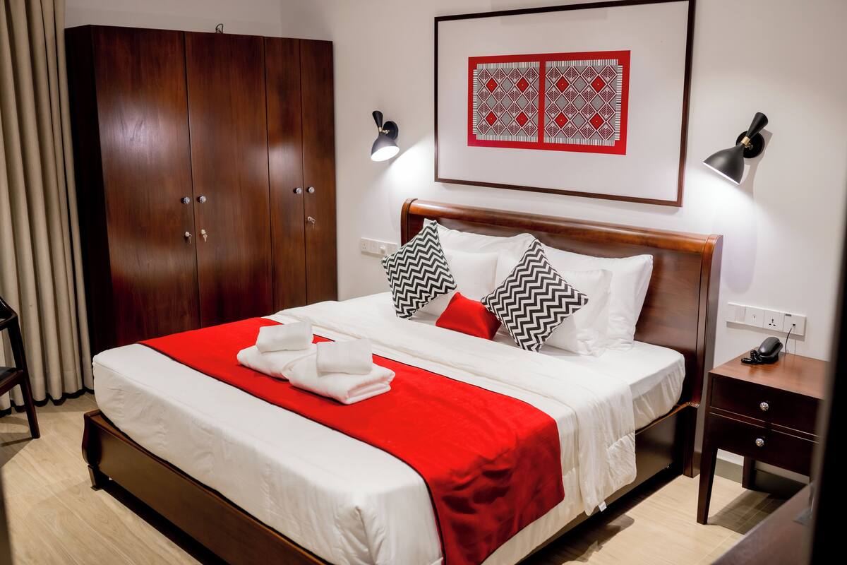 Ein Hotelzimmer mit einem großen Bett, einem Holzschrank, Nachttischlampen und einem gerahmten Kunstwerk an der Wand.