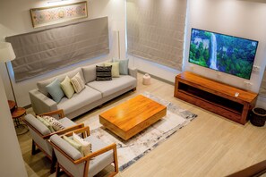 A modern living room with a sofa, coffee table, TV, and a lamp. - Alankara Retreats Colombo 07 (Colombo)