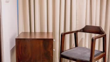 Una silla de madera y una mesa de madera a juego en una habitación con cortinas de colores claros y suelo de madera.
