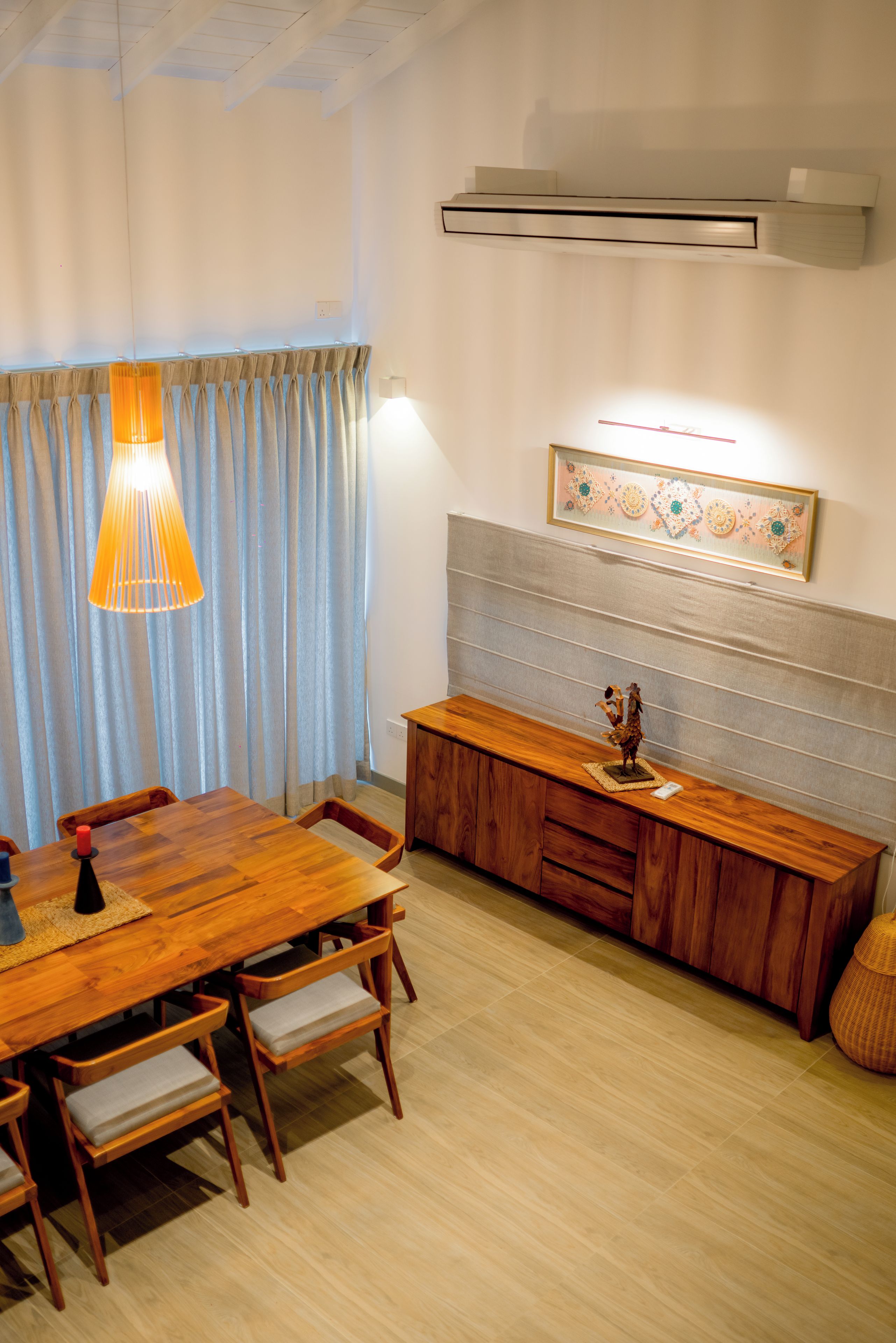 A dining area with a wooden table, chairs, a bench, and a hanging light fixture.