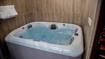 A modern bathroom with a wooden wall, a white bathtub with a built-in heater, and a towel rack above it.