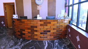 A reception desk with a circular logo, a brick-patterned counter, and a marble floor.