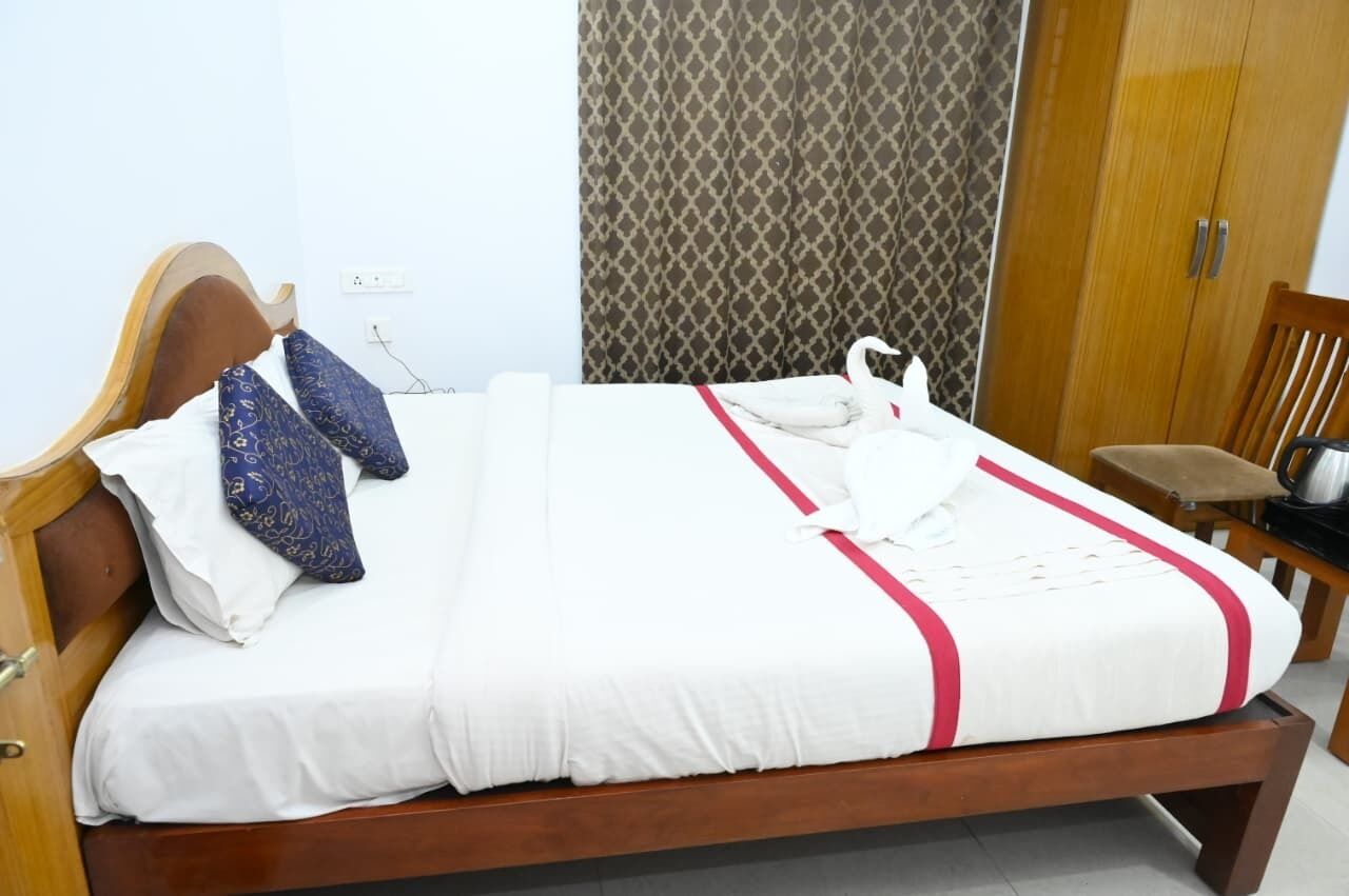 Cama bem arrumada com colcha branca e vermelha, duas almofadas estampadas e uma almofada em formato de cisne.