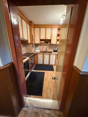 Una cocina con armarios de madera, estufa, lavaplatos y un tapete negro.