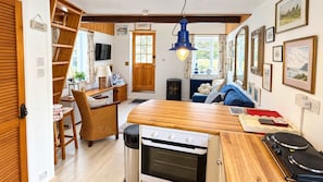 Eine kompakte Küche mit Backofen, ein Essbereich mit Holztisch und eine gemütliche Sitzecke.
