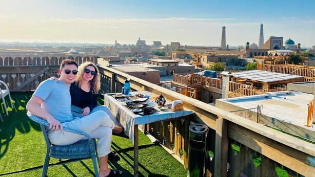 Une terrasse sur le toit, avec une table dressée, d’où l’on peut admirer un panorama sur la ville, avec ses bâtiments historiques et son minaret.