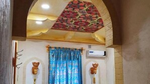 Une chambre avec deux lits, un plafond décoré de motifs et un sol aux couleurs vives.