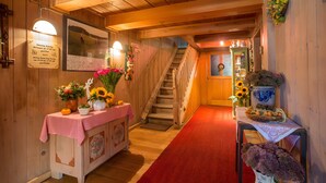 Un intérieur en bois avec un escalier, une table décorée de fleurs et un panneau fixé au mur.