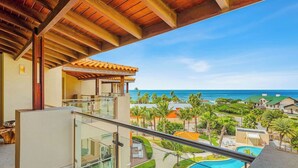A balcony with a glass railing overlooking a pool and a view of the ocean. - 2 Mins to Beach w/ Ocean & Pool Views by Bocobay (Noord)