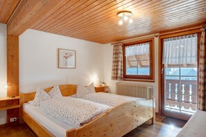 Una cama de madera en una habitación con techo de madera, una ventana con cortinas y un radiador.